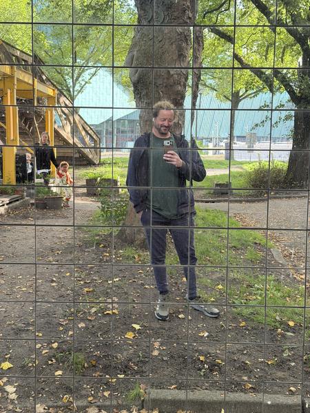 A person smiles while taking a selfie in a large reflective grid at Commandantsbrug, Marineterrein, Amsterdam